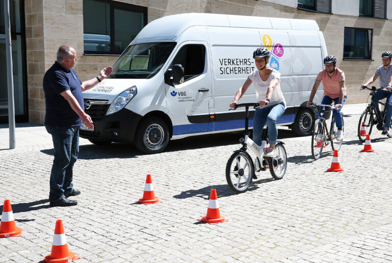 Drei Radfahrer beim Fahrtraining unter Anweisung eines VBG-Ausbilders.