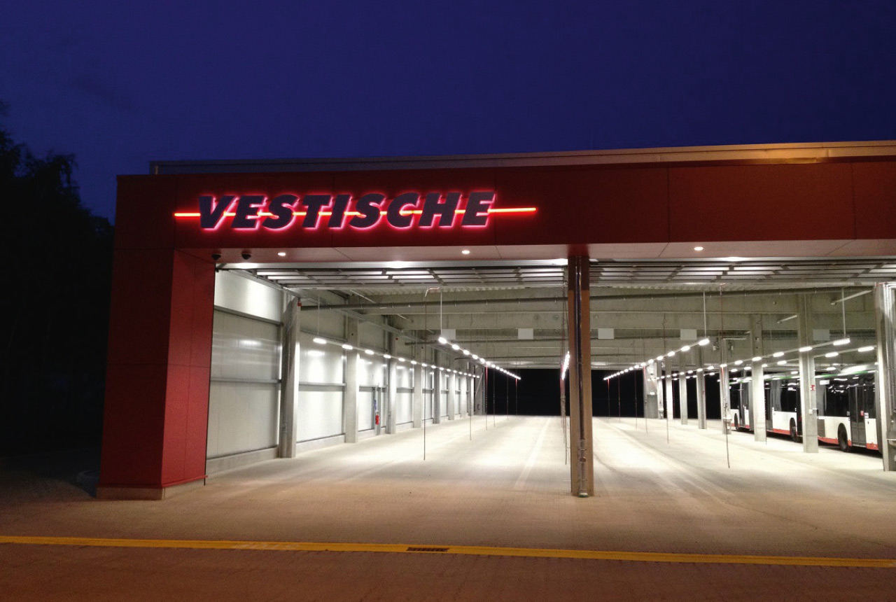 neue Abstellhalle für Busse in der Nacht, innen hell erleuchtet, mit leuchtendem Schriftzug „Vestische“